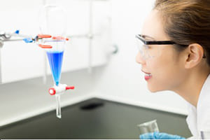 Researcher Looks at A Separatory Funnel